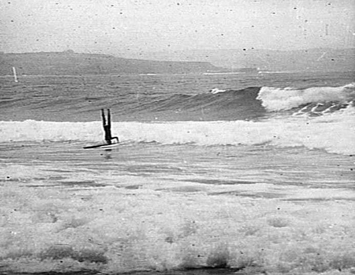 Man doing a head-stand on a surfboard, Freshwater Beach