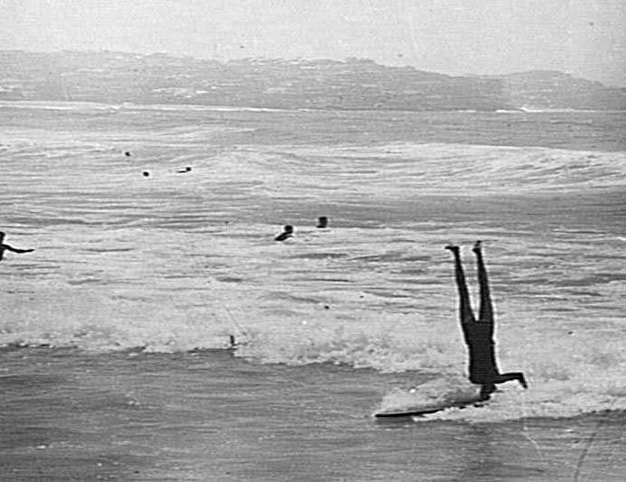 A man doing a head-stand on a surfboard, Manly