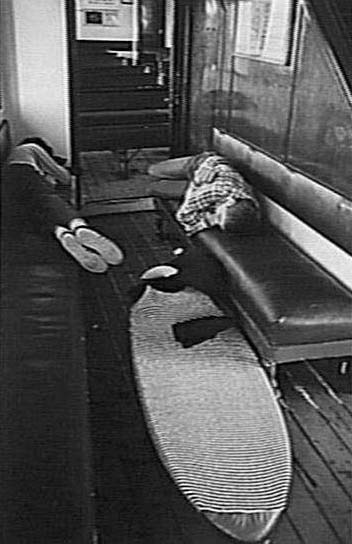 Two surfers asleep on benches aboard a Manly Ferry