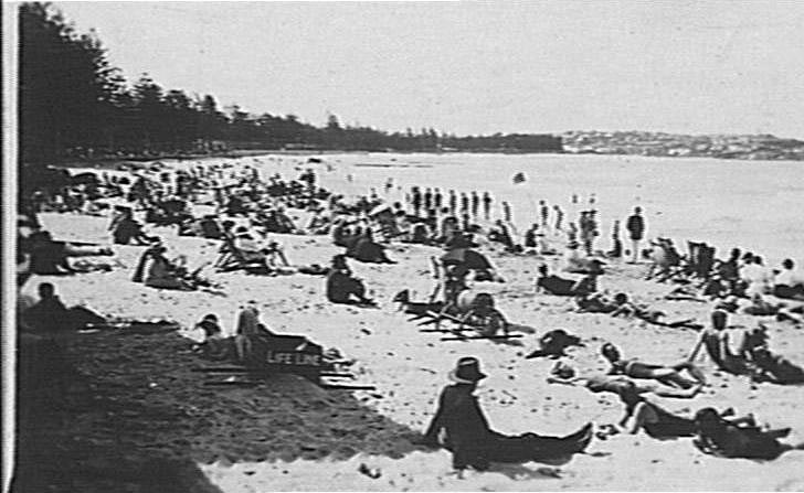 View of Manly Beach showing people and an early-style life-line