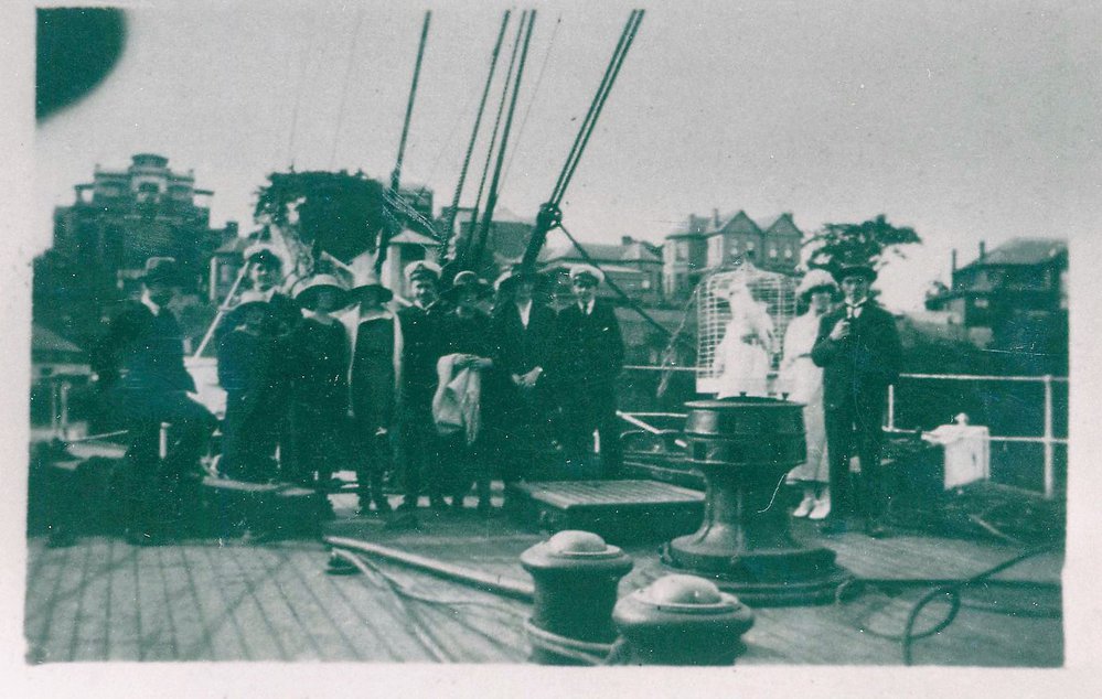Passengers, crew and cockatoo on the deck of a docked sailing boat, Hawkesbury River