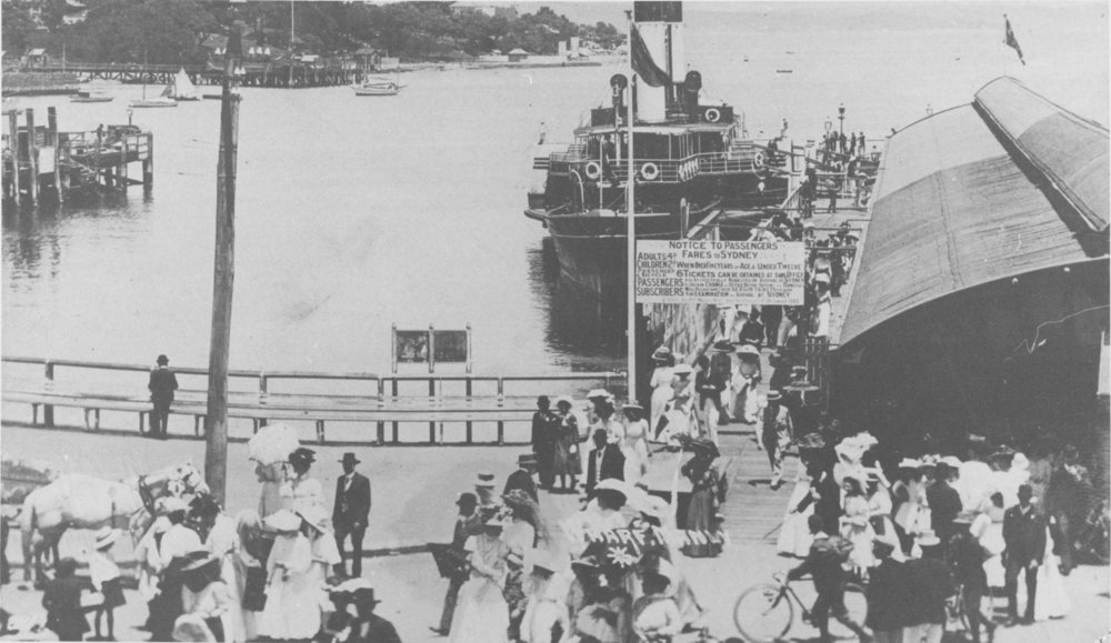 Commuters at Manly Wharf, showing the cargo wharf and eastern shore, and a paddle steamer moored at the wharf, c1910