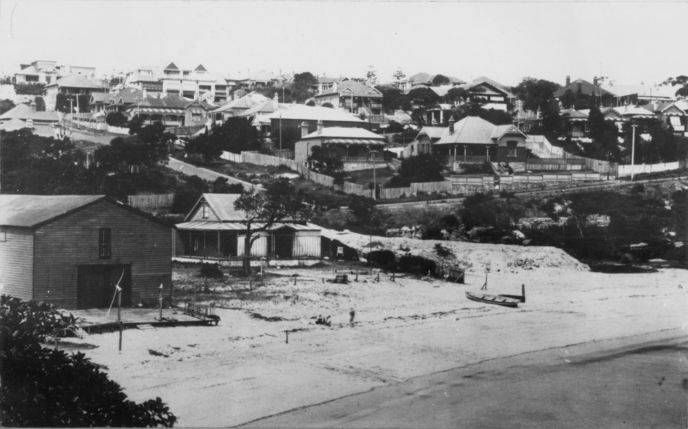 View facing east over Little Manly Cove, showing a boatshed and houses covering the hillside