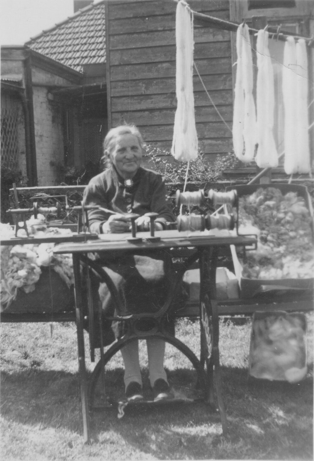 Unidentified woman sitting at a loom with weaving in the background, date unknown