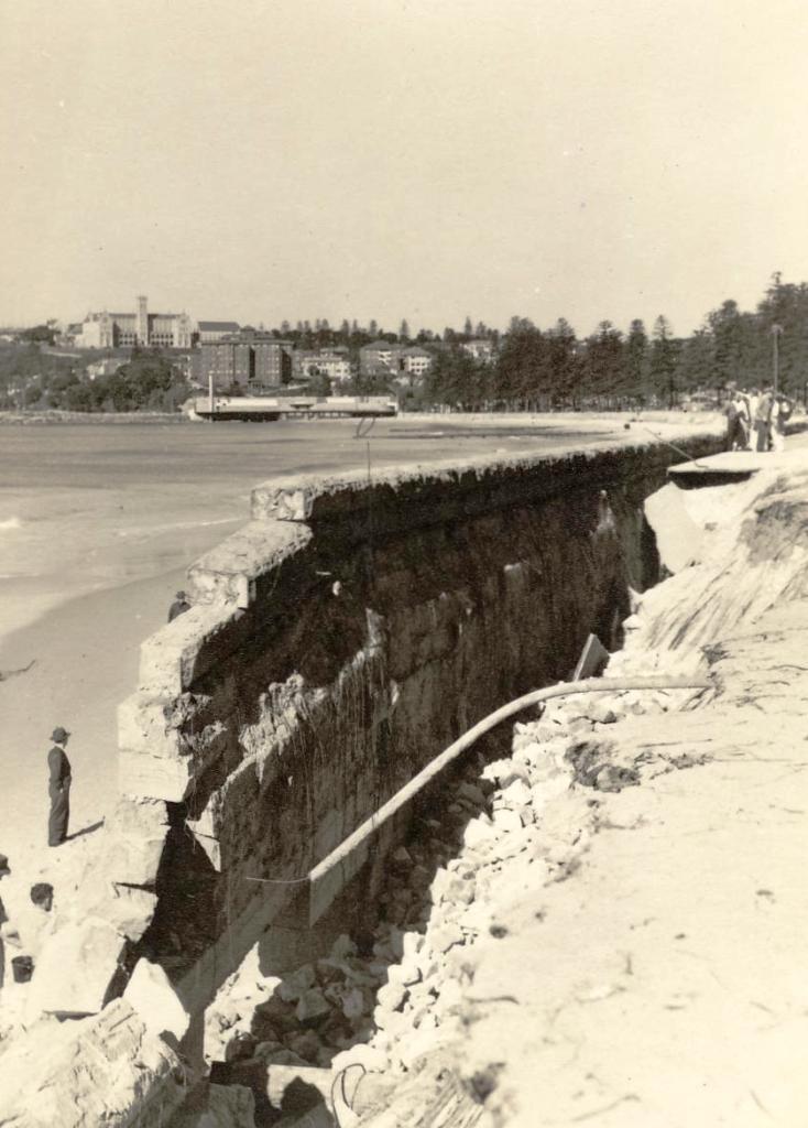Collapsed sea wall, North Steyne, with St Patrick's Collge and Borambil flats in the distance, Manly, 27th June 1950