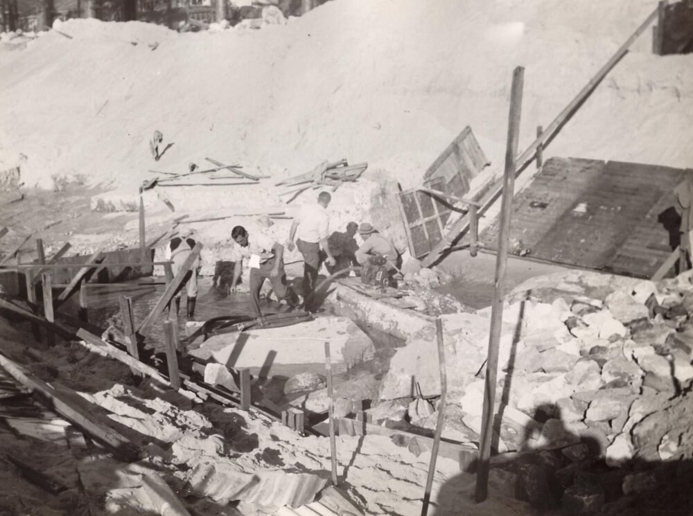 Construction continues on sea wall, showing workmen and debris in channel, North Steyne, Manly, 1955