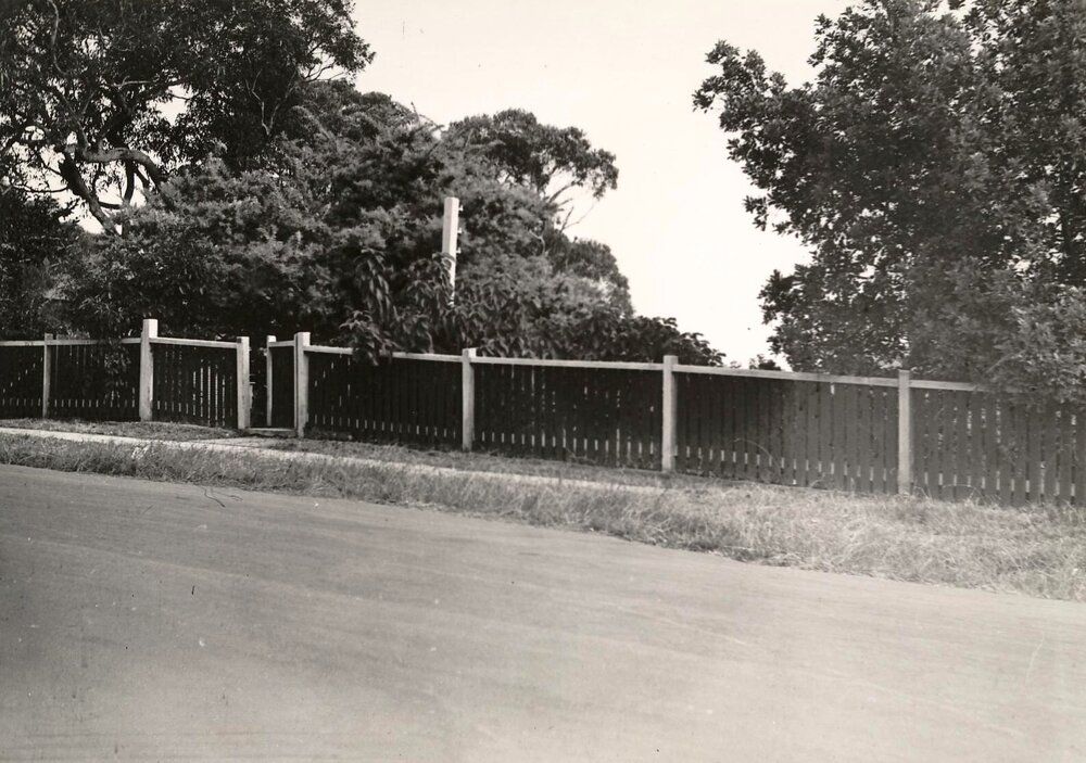 Street view of fence and gate along property boarder, c1940s