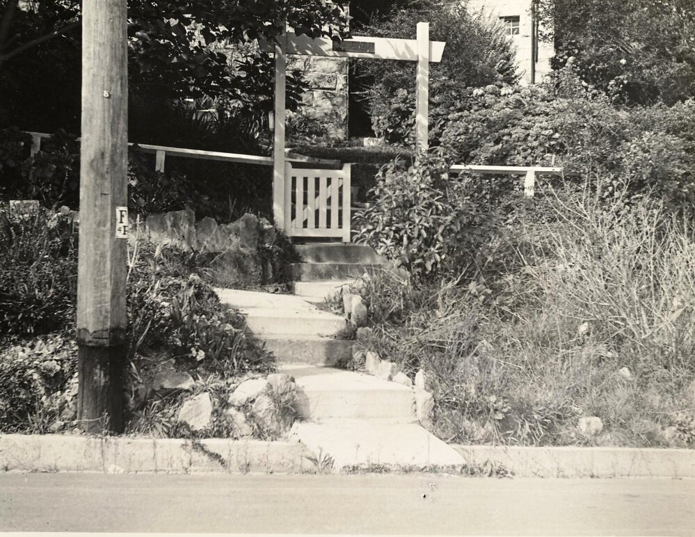Streetview of front steps and garden beds of a house, c1940s