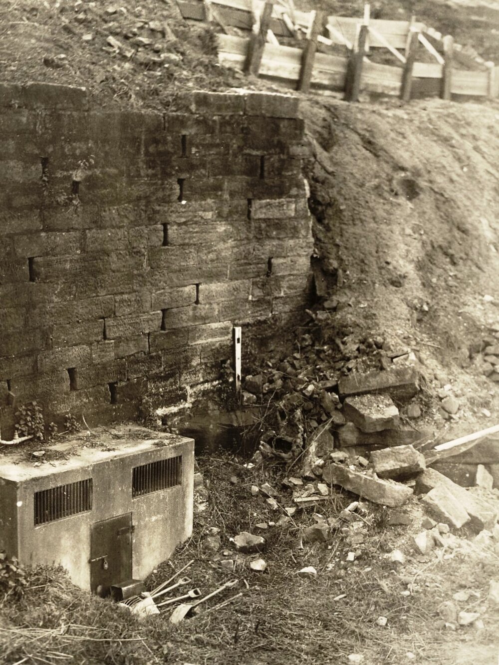 Earthworks continue at unidentified site, brick wall and supports visible, c1940s