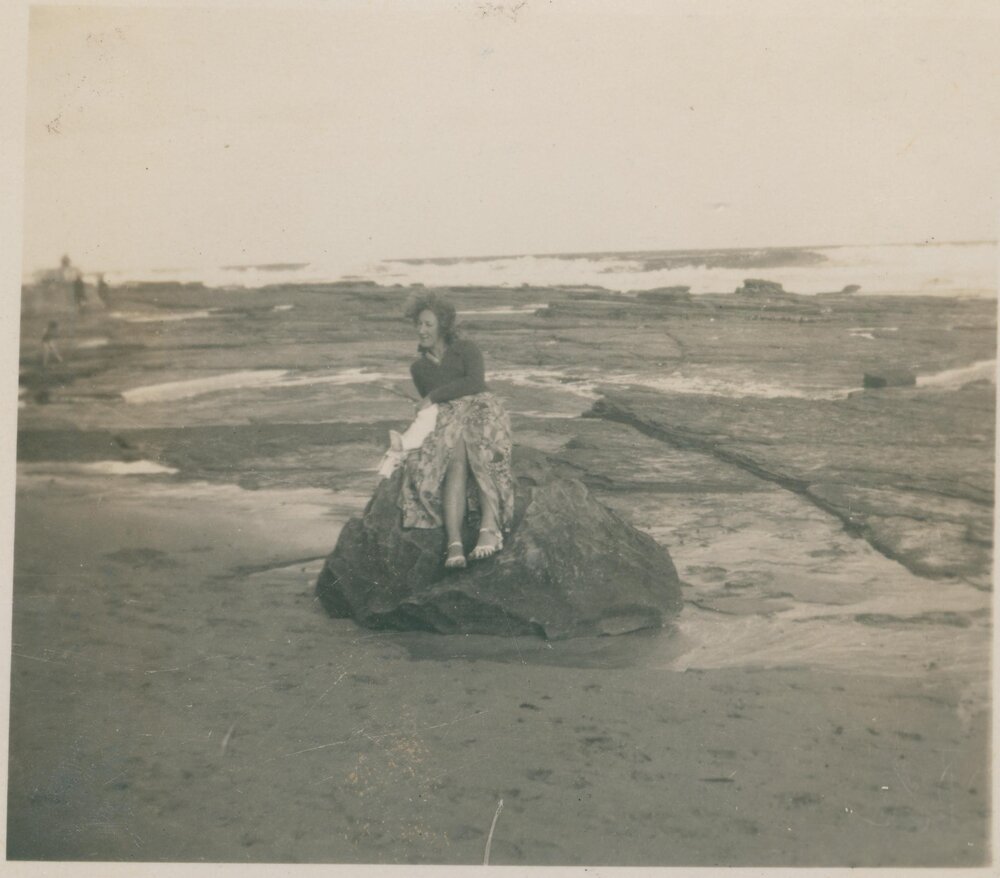 A woman sitting on a large rock at Narrabeen Beach, Narrabeen, 1943