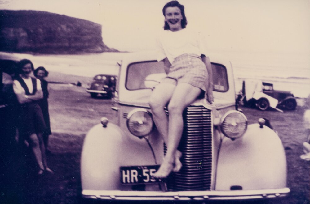 Dorothy Groom sitting on bonnet of car with license plate HR 551, Bilgola Beach, 1948