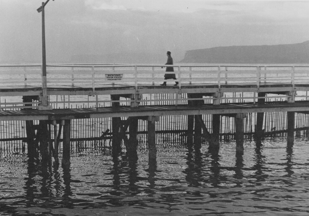 A person walking across the old Manly boardwalk, Manly, c1967-1973