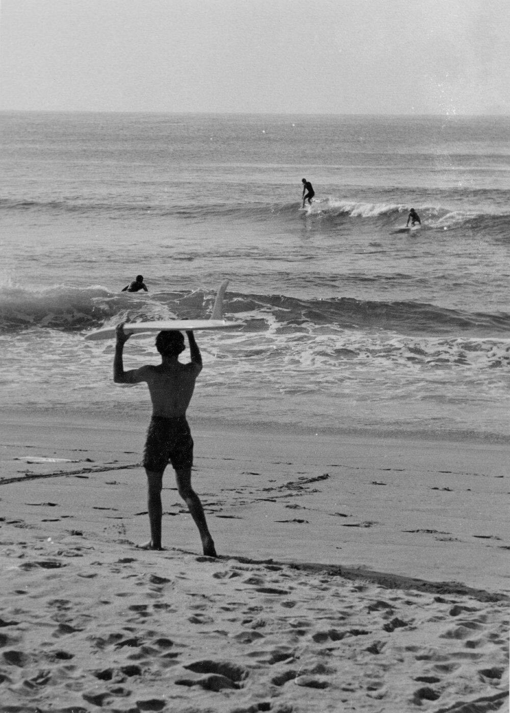 Surfer heading into the water at Manly Beach, Manly, 1972