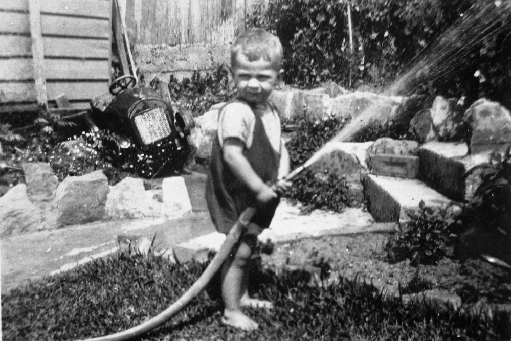 Keith Sterland playing with garden hose, 43 Crown Road, Queenscliff