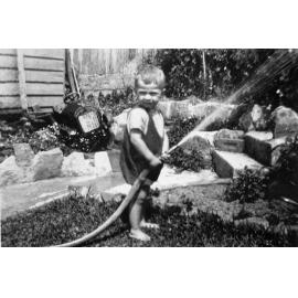 Keith Sterland playing with garden hose, 43 Crown Road, Queenscliff