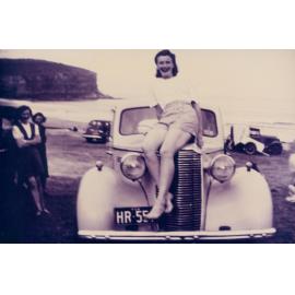 Dorothy Groom sitting on bonnet of car with license plate HR 551, Bilgola Beach, 1948