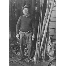Unidentified elderly man in a boatshed