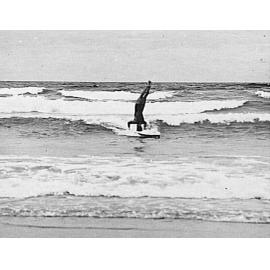Man doing a head-stand on a surfboard, Freshwater Beach