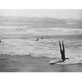 A man doing a head-stand on a surfboard, Manly