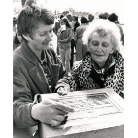 Barbara Murray and Ella Westwood inspecting a plaque, Manly