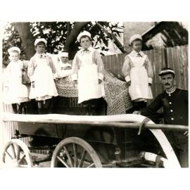 Fireman standing beside five children on fire brigade handcart