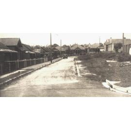 View of street with parked car and houses, c1940s