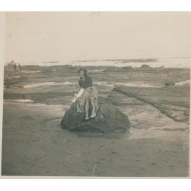 A woman sitting on a large rock at Narrabeen Beach, Narrabeen, 1943
