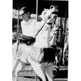 Man leaning over a horse on the carousel at Manly Fun Pier, Manly, c1967–1973