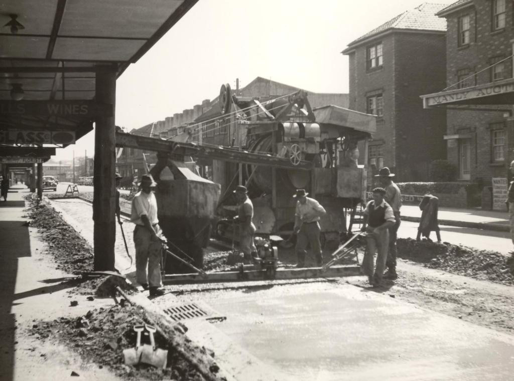 LH011058 - Concreting mixing and pouring unit with work crews in Pittwater Road, Manly, 24th September 1949